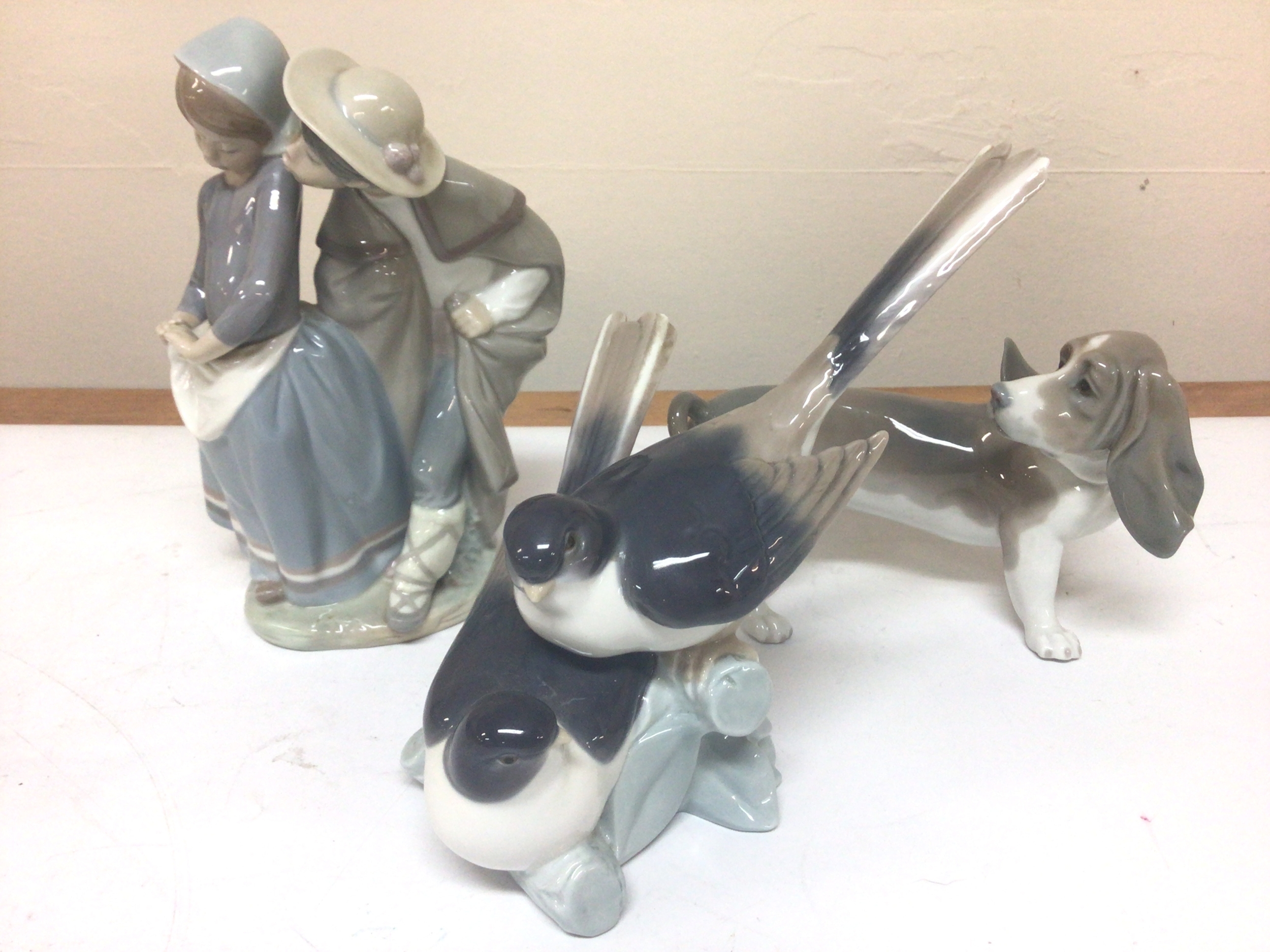 Three Lladro porcelain figures a dog, a group of birds and a young courting couple maximum hight 22cm no obvious damage. (3)
