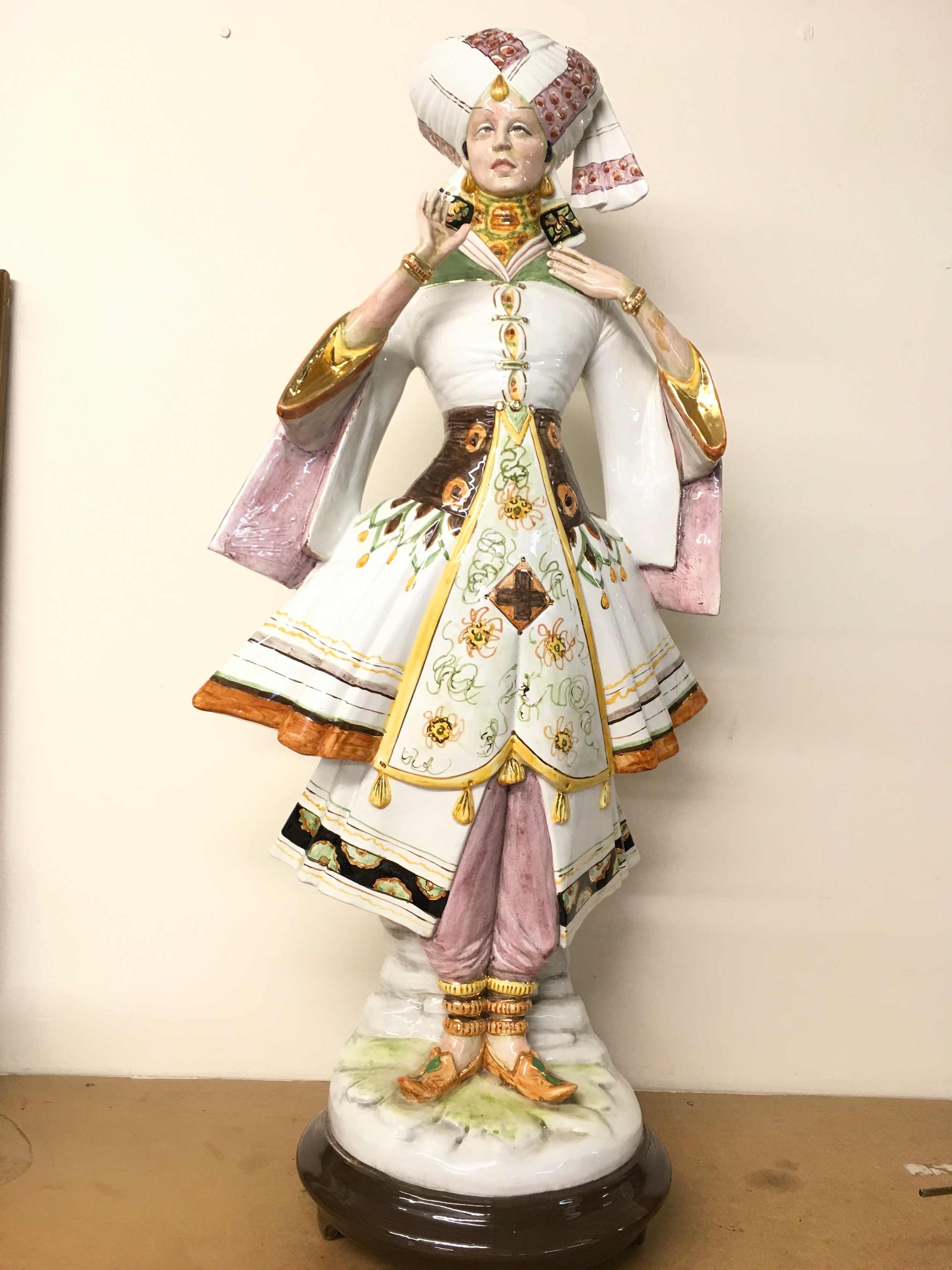 A large ceramic figure of an elaborately dressed Eastern figure in a patterned turban, signed on the back Italian Artist Domenico Poloniato (1926–2013). Approximately 73cm tall. There is crazing and some small paint chips