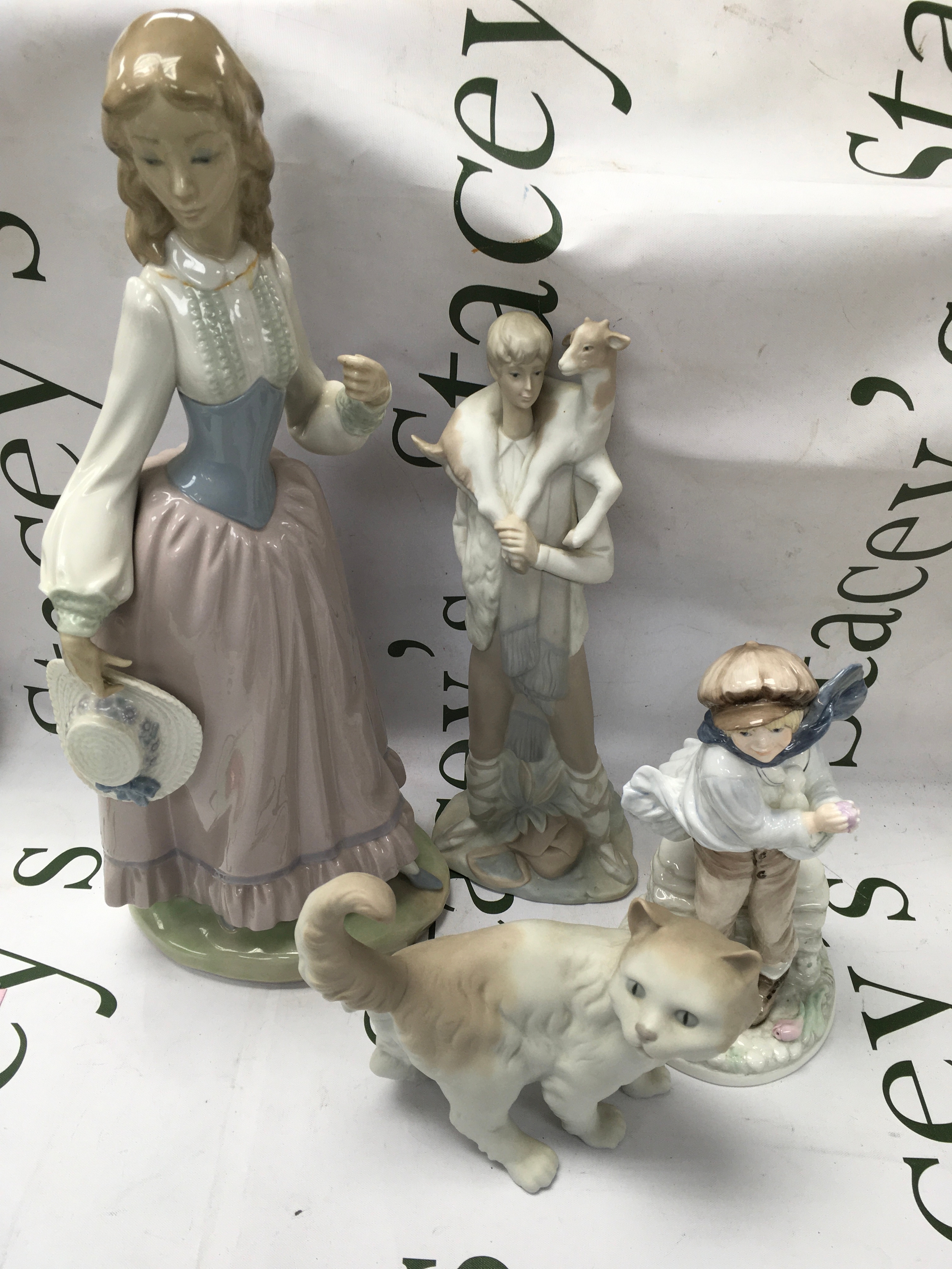 A collection of two Lladro figures, a Nao cat figure and a Coalport child figure 
