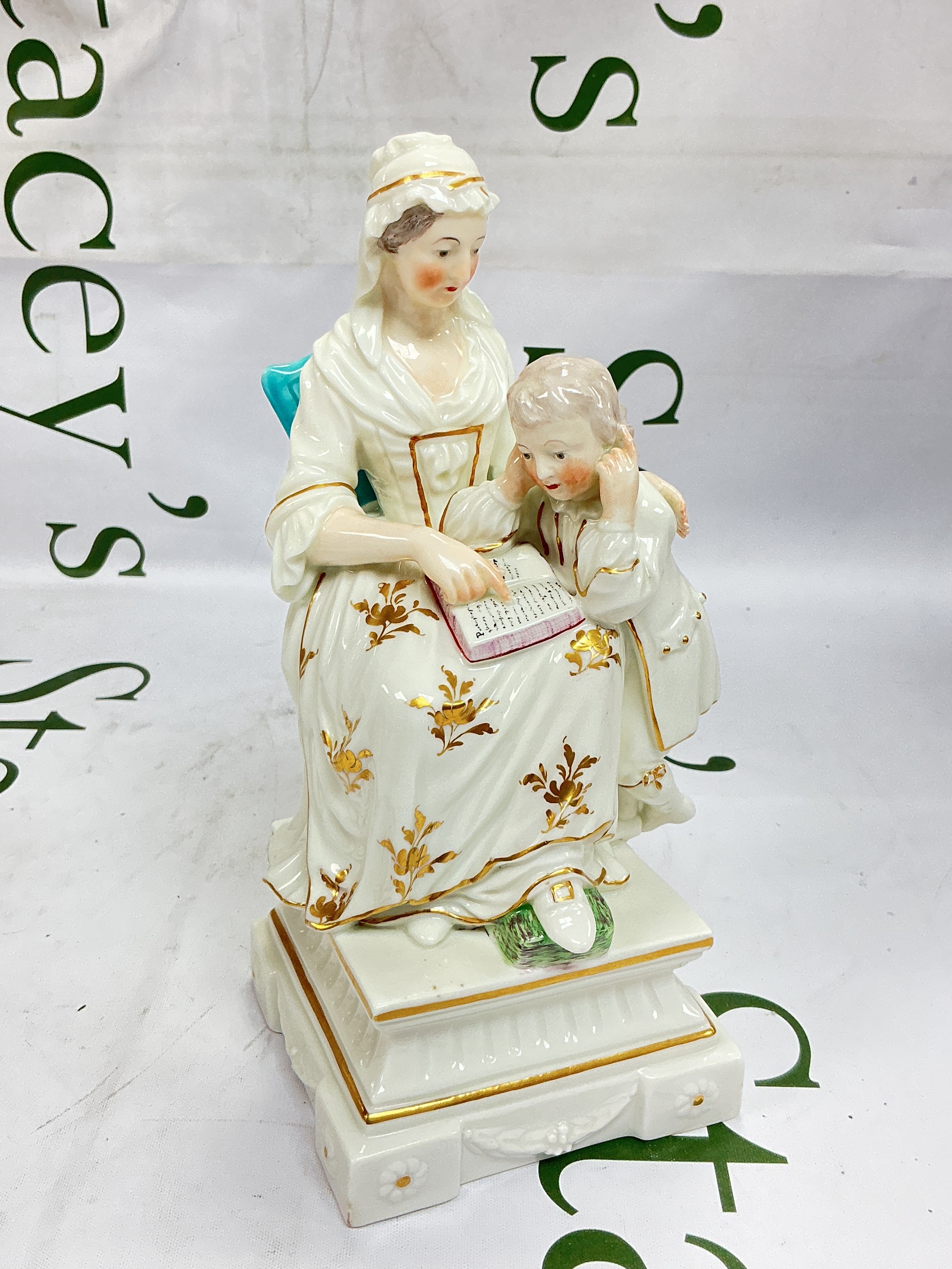 A circa 1775-90 Derby porcelain figure group titled 'The Prudent Mother'. Modelled as a mother and child seated on a turquoise chair and raised in a relief moulded Neo Classical base, approx height 20cm. Base is cracked to reverse.