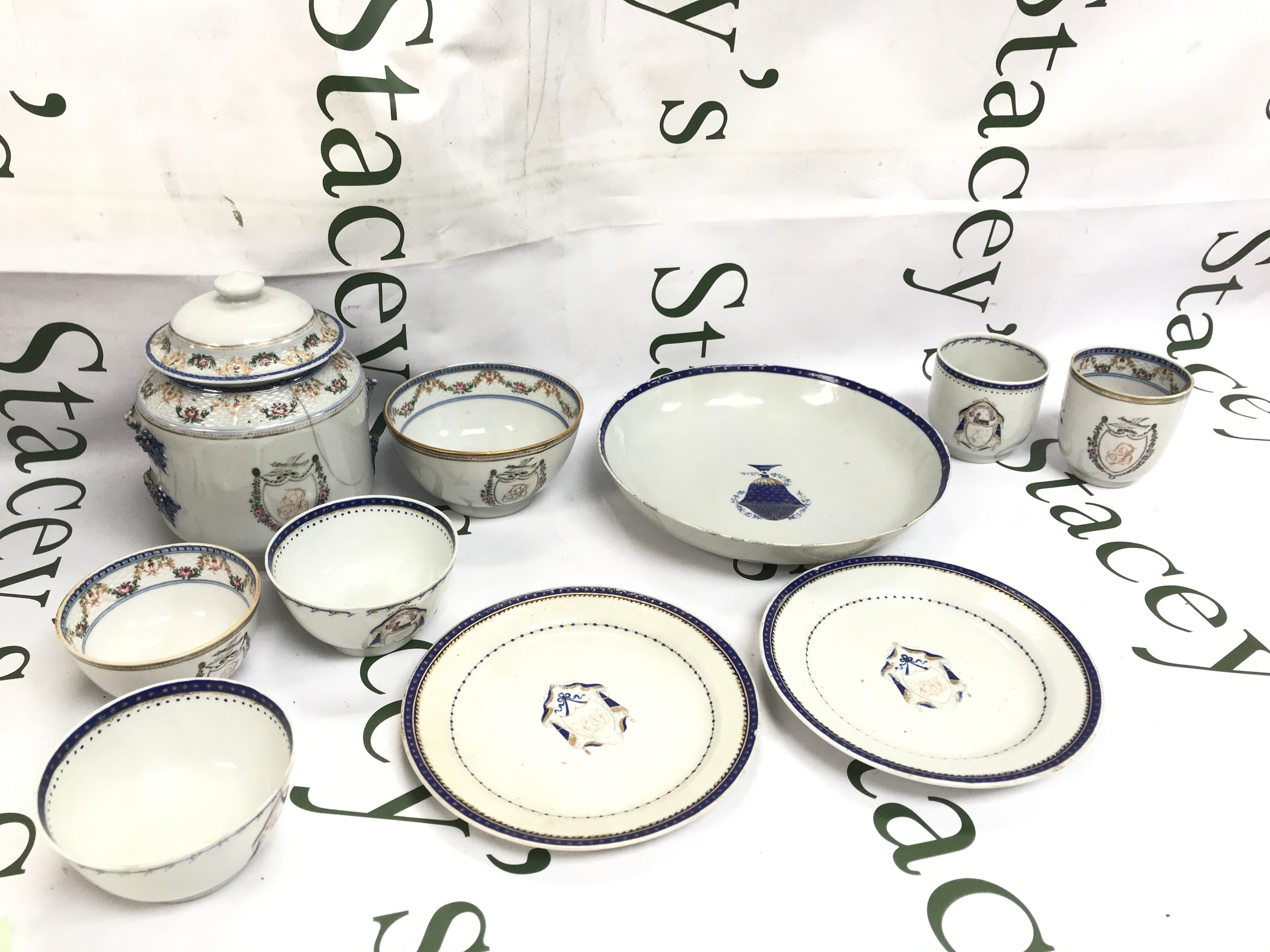 18th-century Chinese export Qianlong period armorial porcelain tea and tableware service, featuring blue and white patterned borders with central armorial crests. Damage and hairline cracks