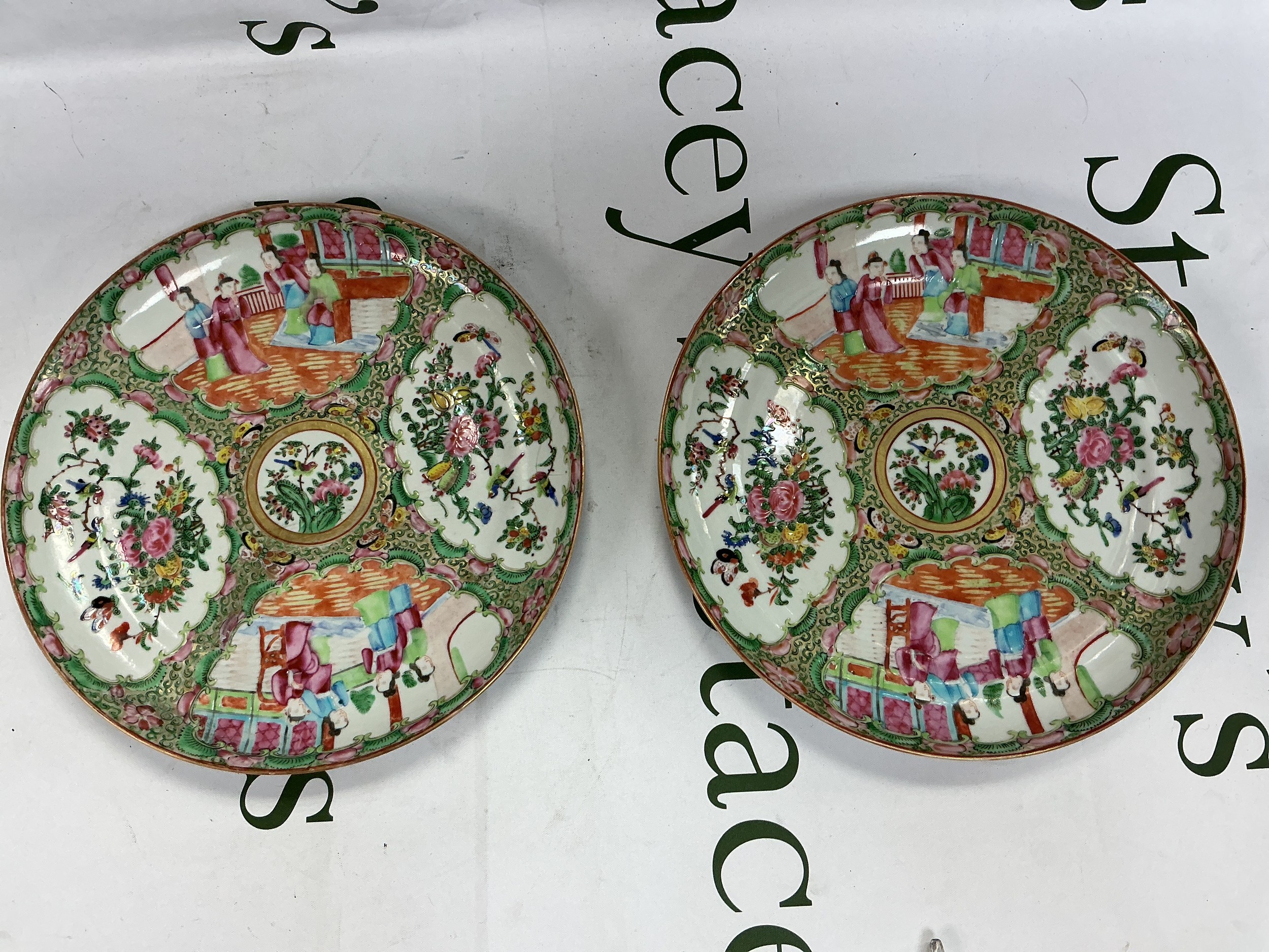 A pair of famille rose plates decorated with figures, birds and foliage, approx diameter 25cm. One has been restored.