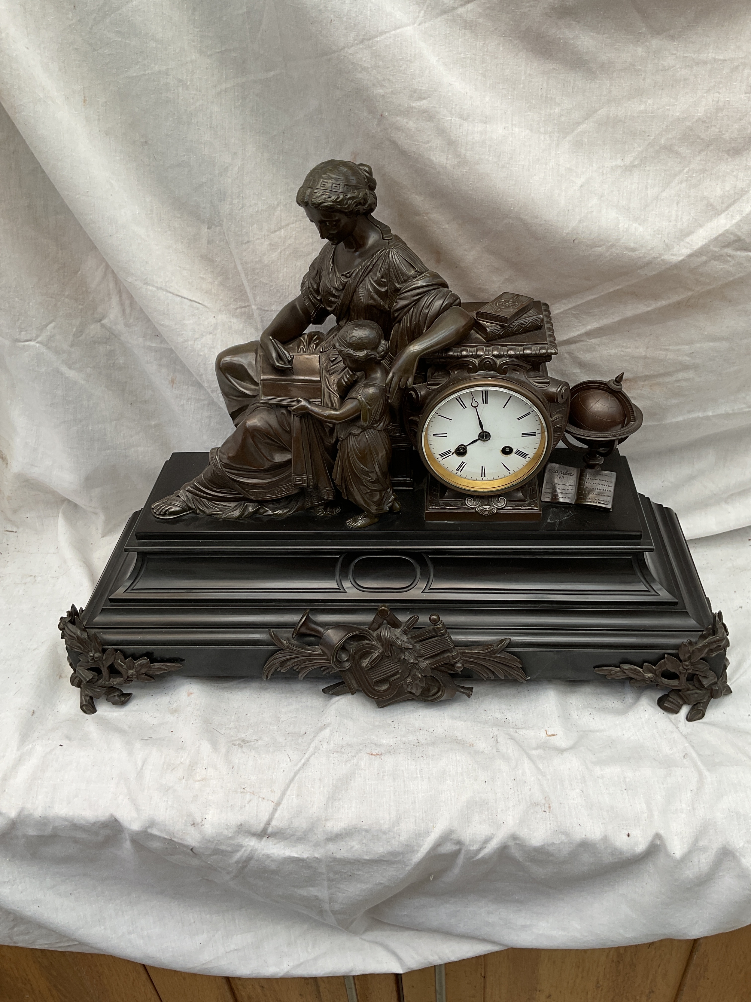 French Bronze and marble clock with mother and child in learning and with books and a moving globe.ornate laurel feet to front and central brocade, square feet to the back,Raingo Freres eight day movement striking on bell. Missing bell but has pendulum. h42 cm x 55cm x 20 cm.