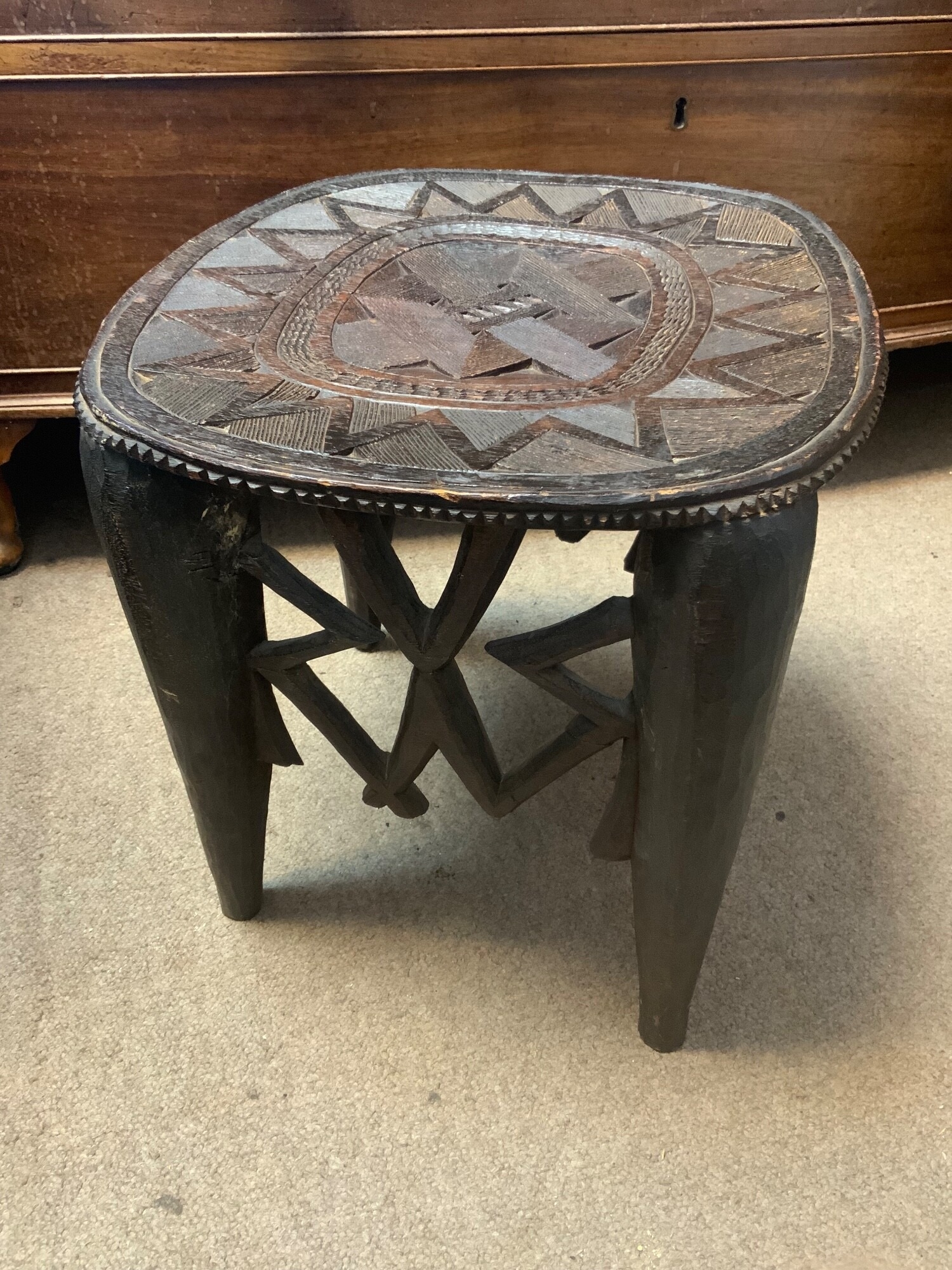 A vintage hand carved Nupe stool from Nigeria with intricate geometric patterns 15" High, together with a hand carved paddle. TO BE SOLD WITHOUT RESERVE