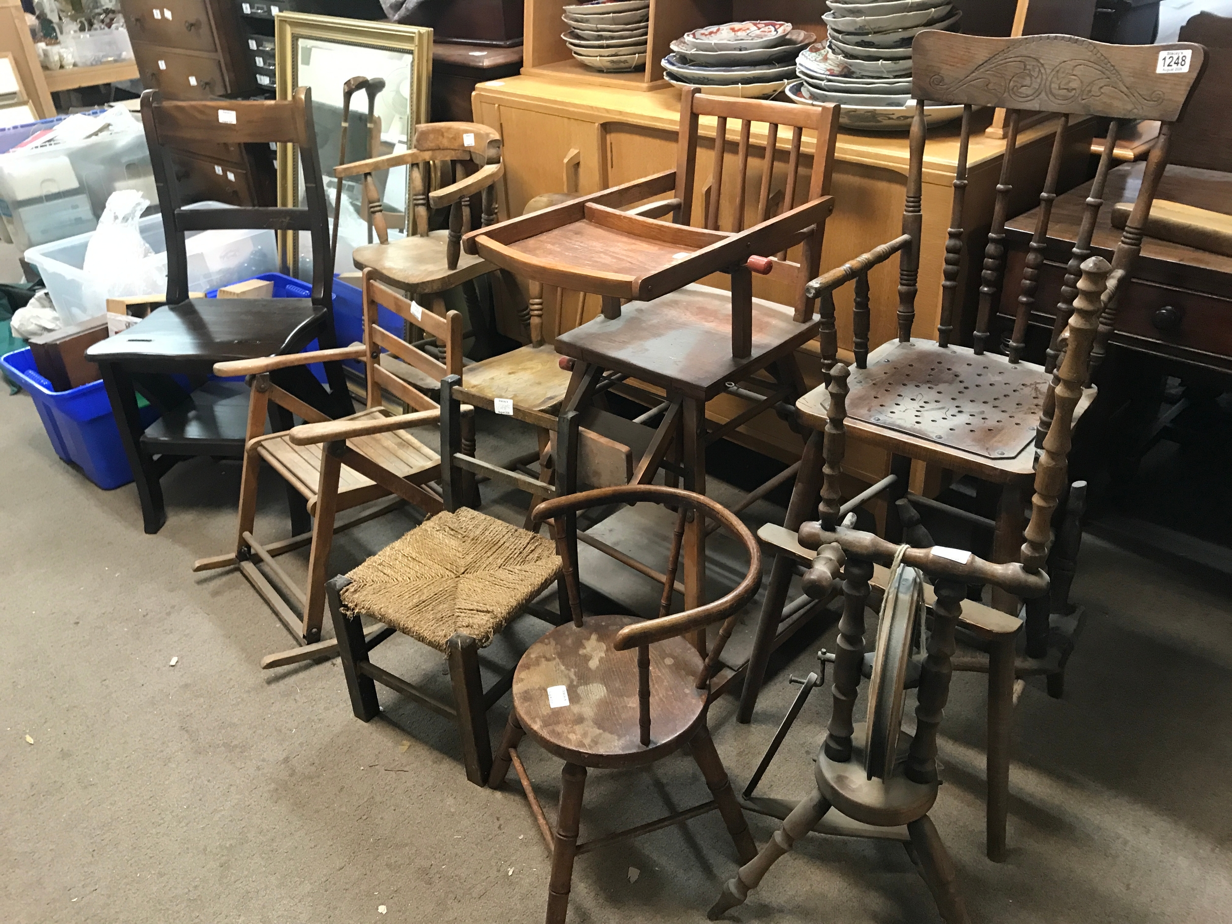 A collection of antique and vintage wooden children's chairs, dark wood metamorphic library chair, high chairs, miniature seating, and a traditional spinning wheel. TO BE SOLD WITHOUT RESERVE