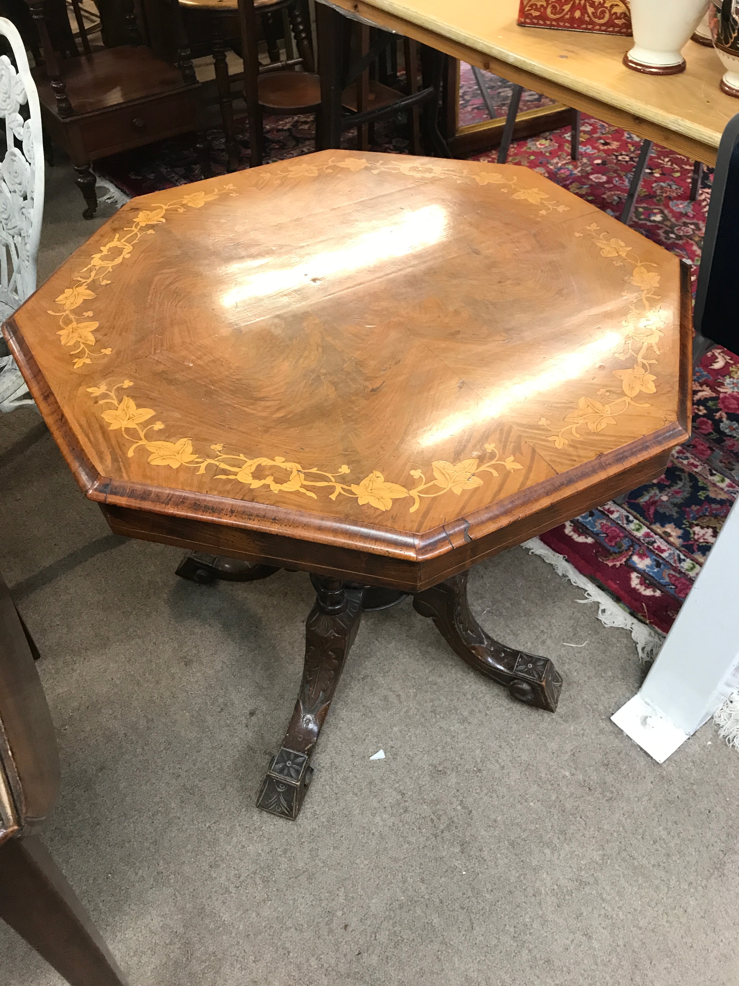 A Edwardian octagonal burr walnut occasional/centre table with inlaid marquetry or floral motif detailing along the border and a carved multi-footed pedestal base. 72cm wide 70cm tall 