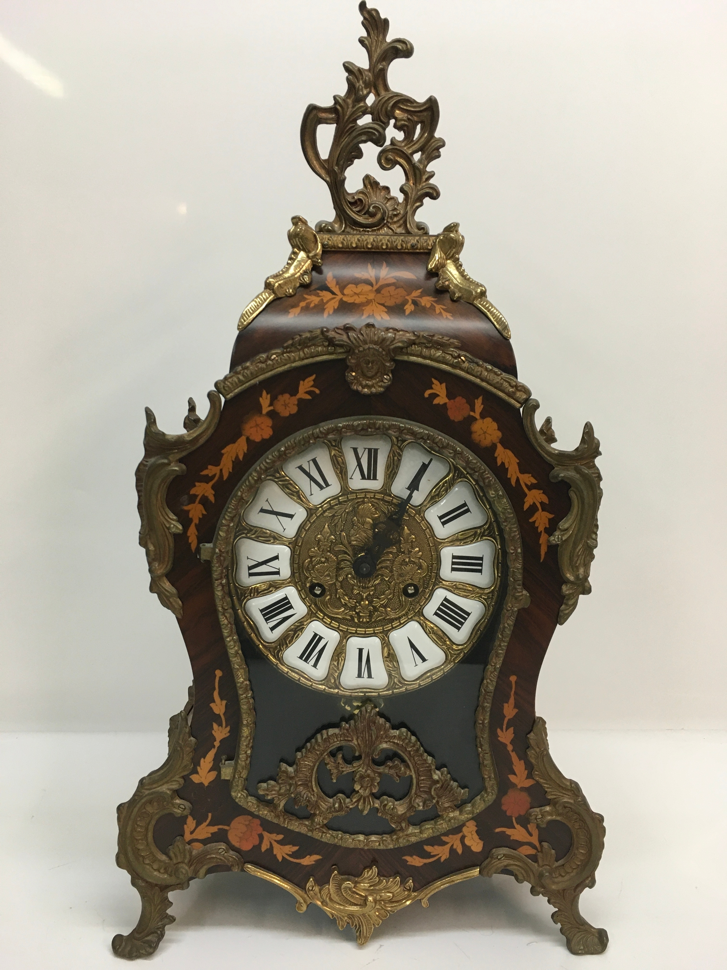 A reproduction French mantle clock of waisted shape, having inlaid style decoration, gilt mounts and enamel dial.Approx 30 x 58cm