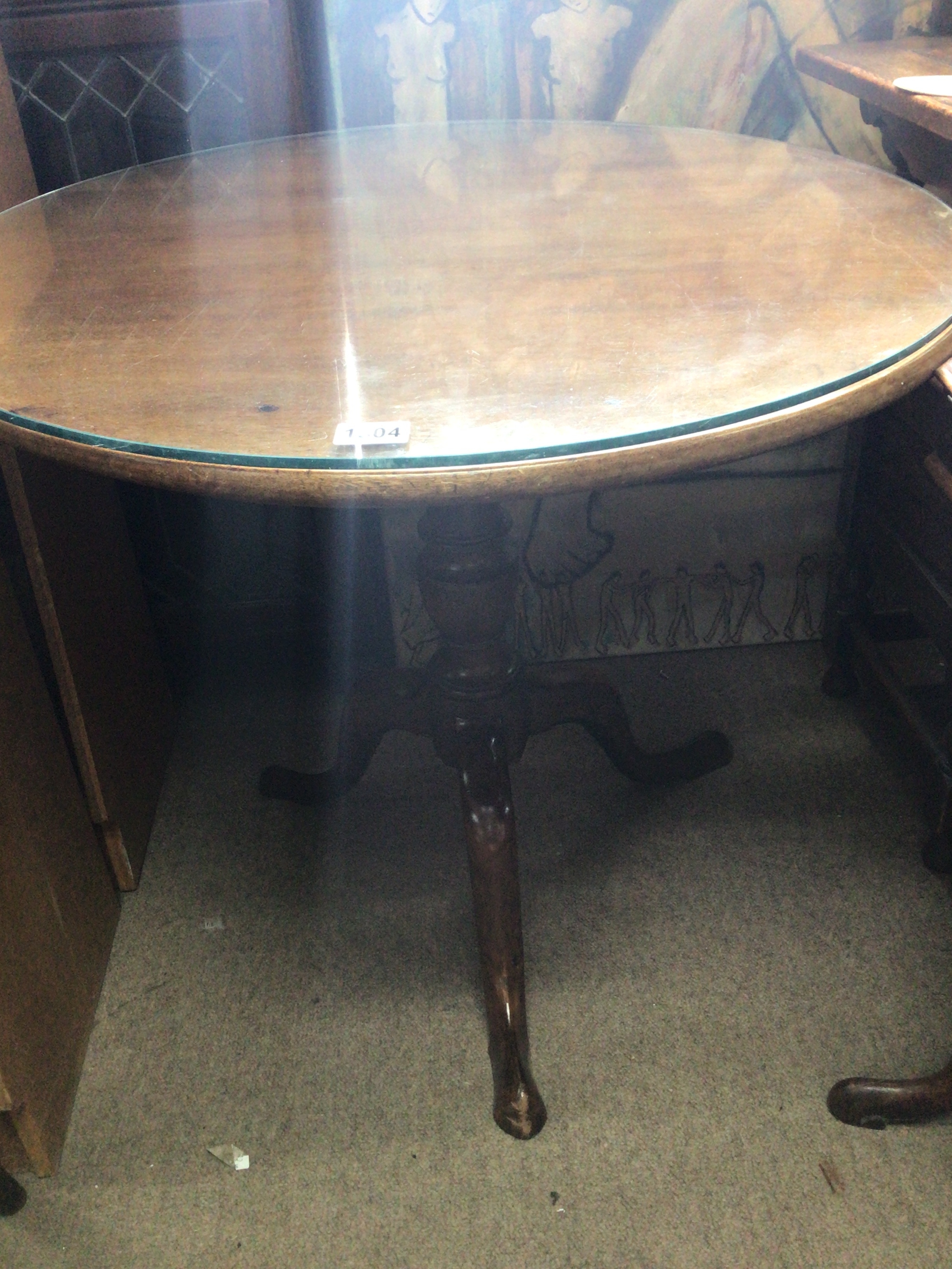 A late George III mahogany tip action table with a glass top the circular top on a turned colum and splayed legs top diameter 67cm diameter.
