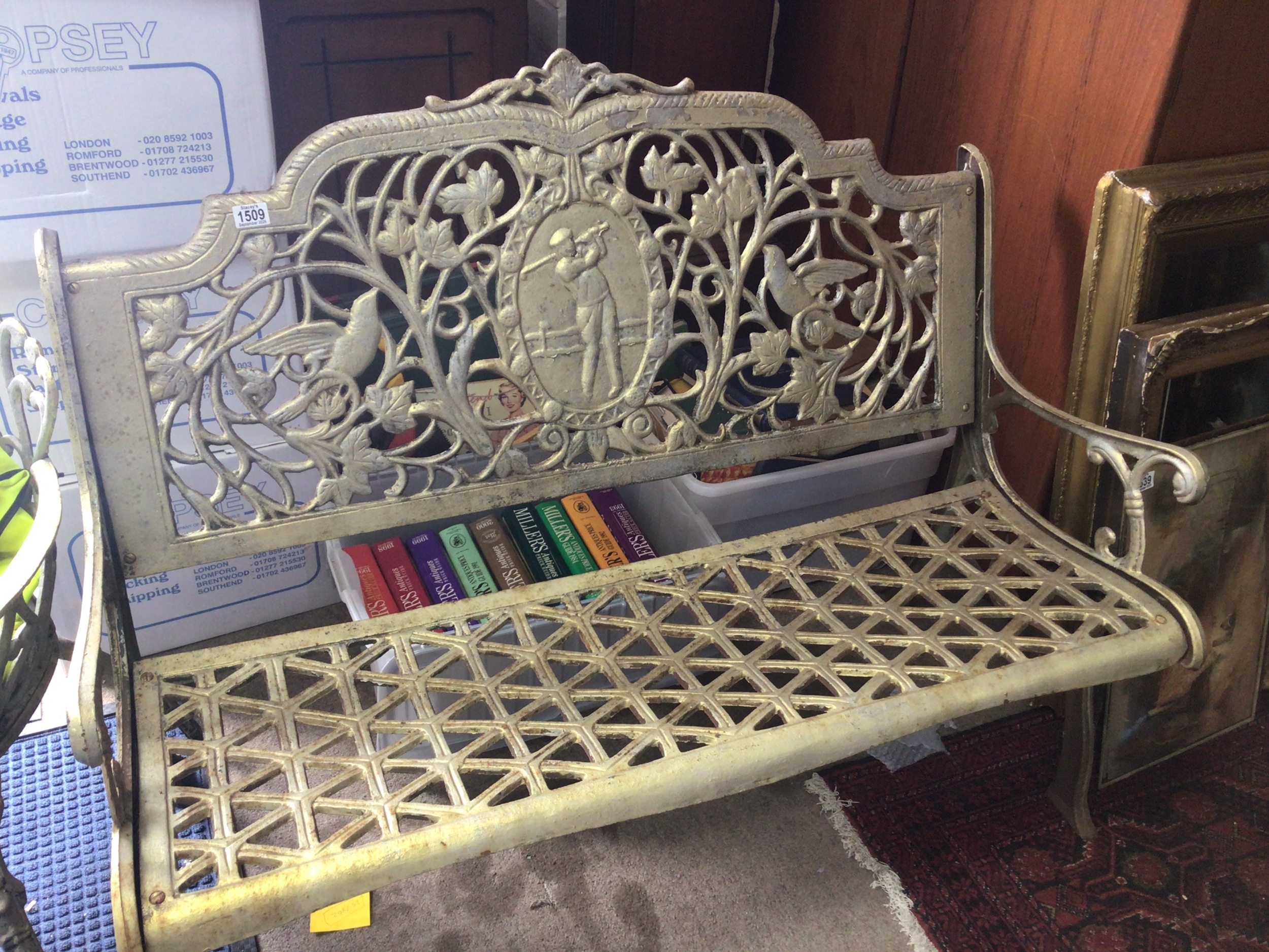 A Vintage cast metal garden bench the back centred by a golfer with open folate scrolls and birds open lattice work seat. length 125cm wide 