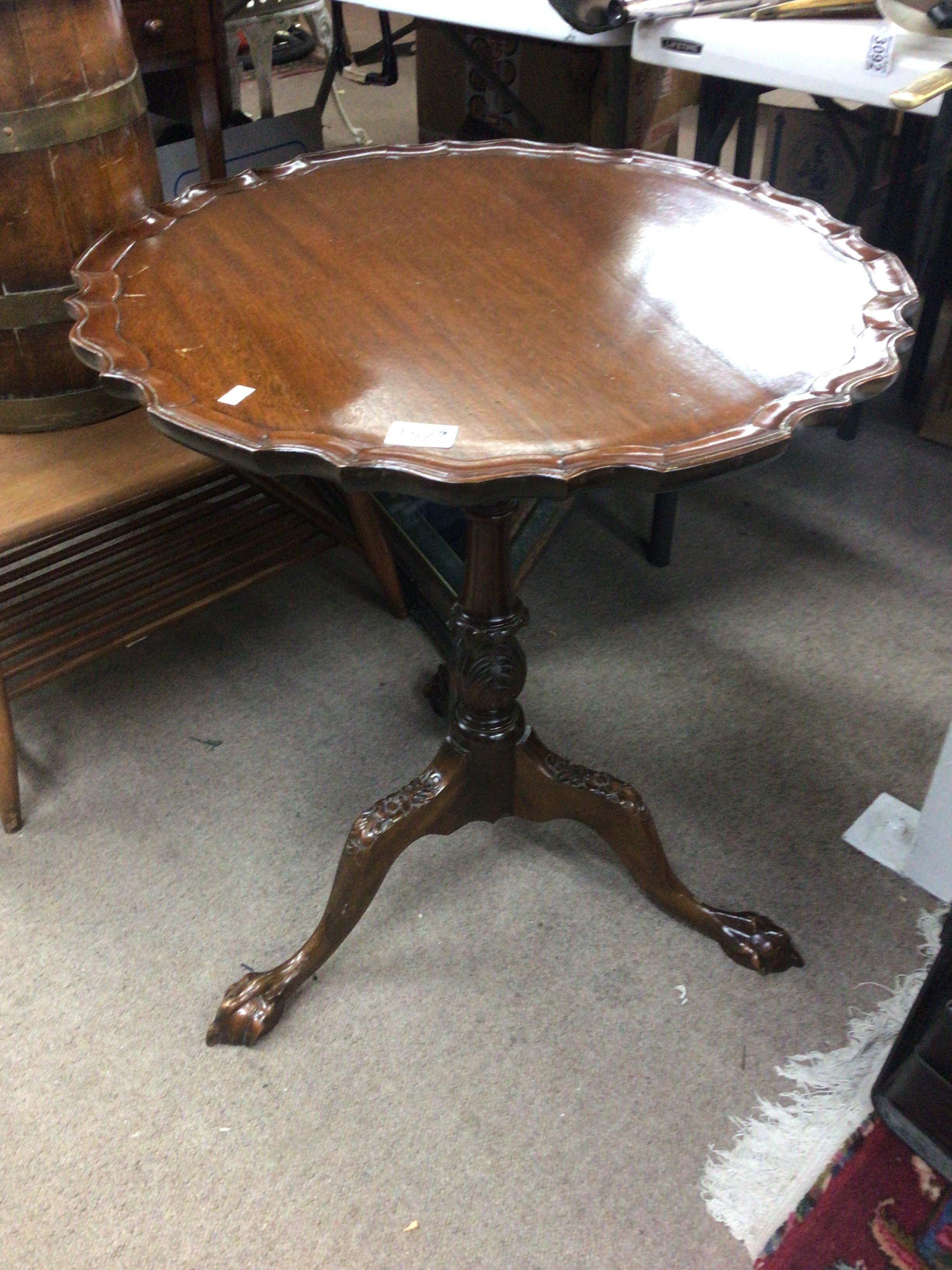  A late George III style tip action wine table with four pillar revolving mechanism the top with a moulded edge on a carved column and splayed legs ball and claw feet.