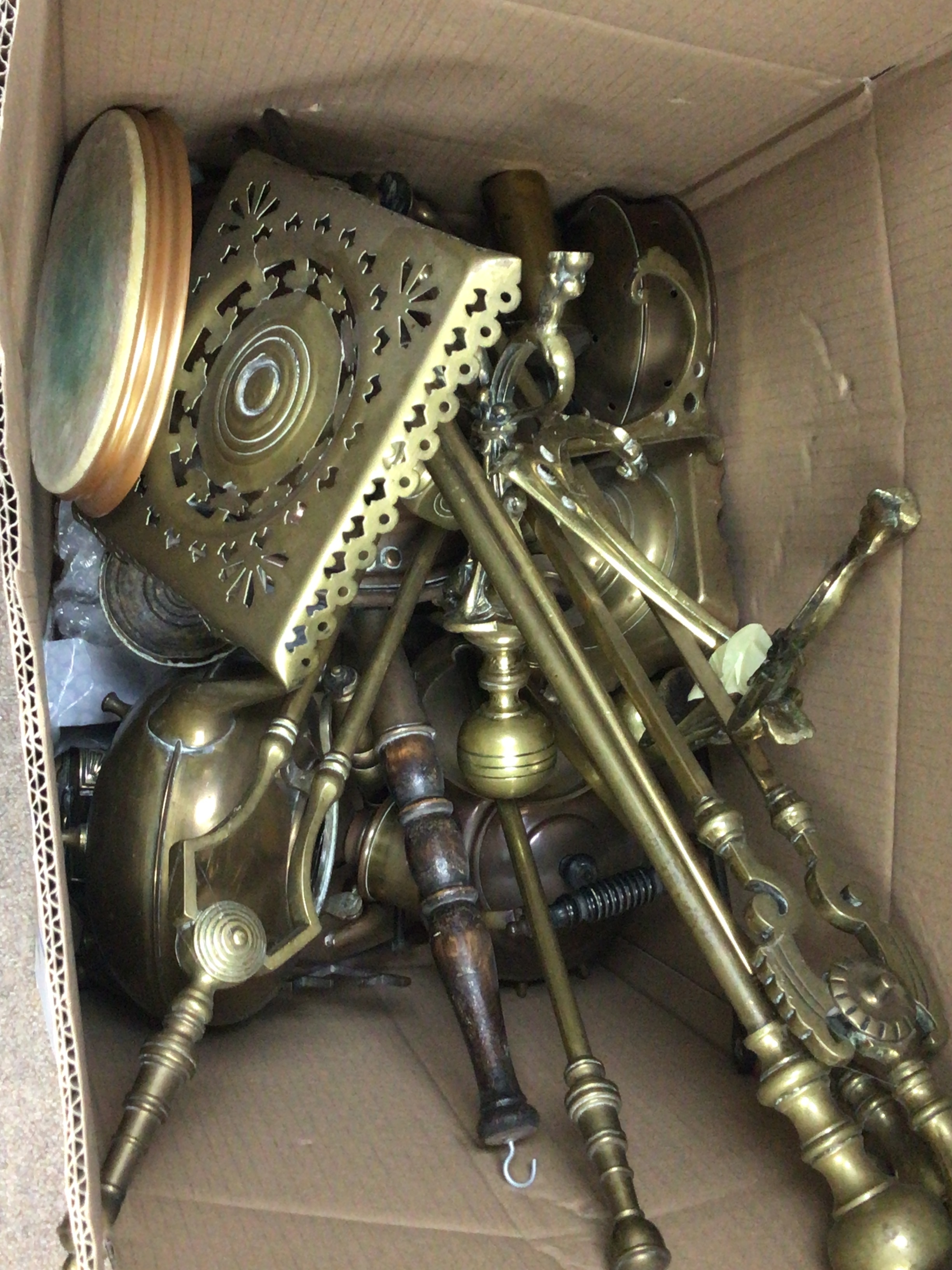 A box containing a quantity of fireside accoutrements fire irons trivets brass kettles 
