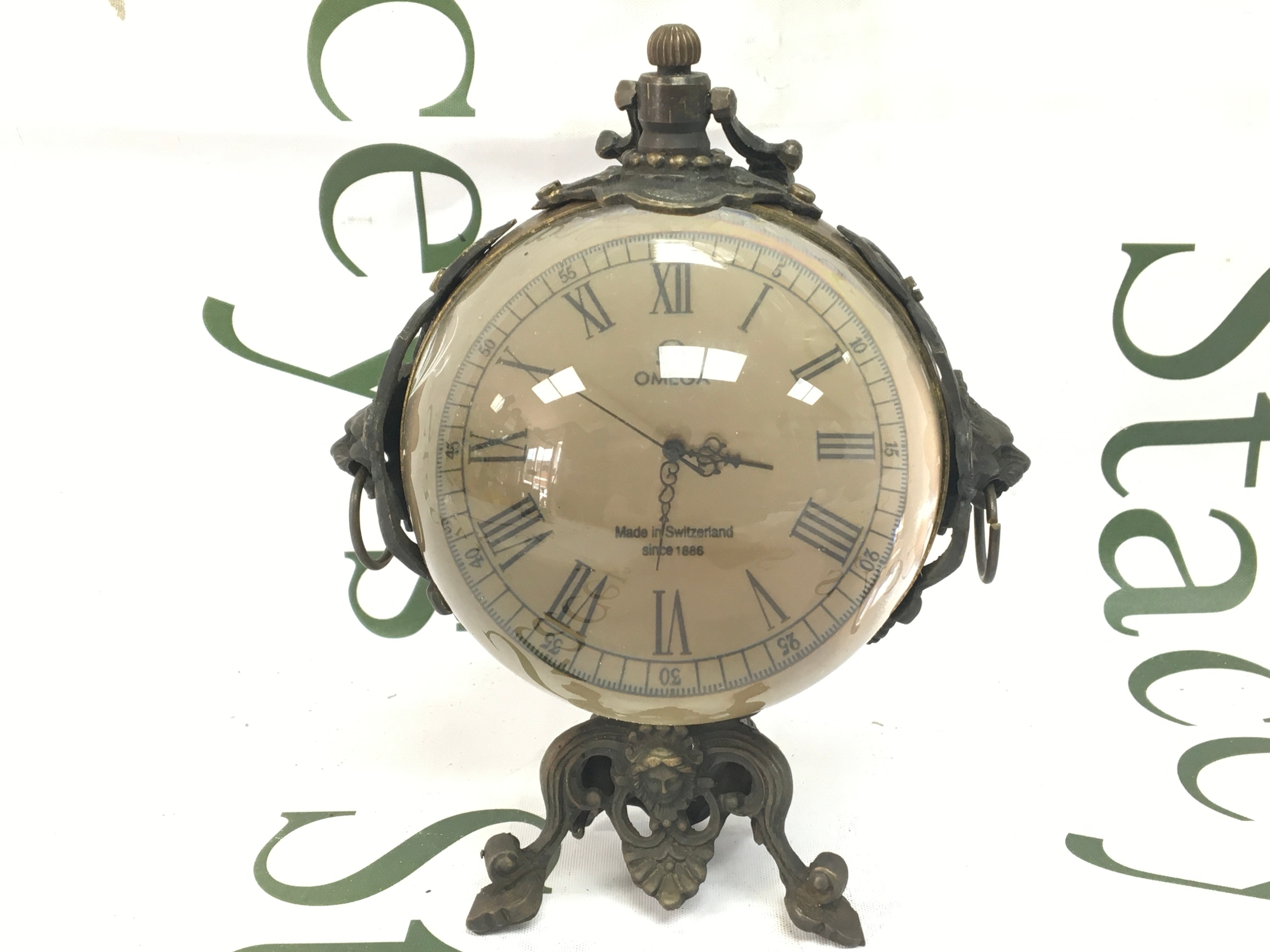 A vintage glass ball clock by omega in working order on bronze base and handle 