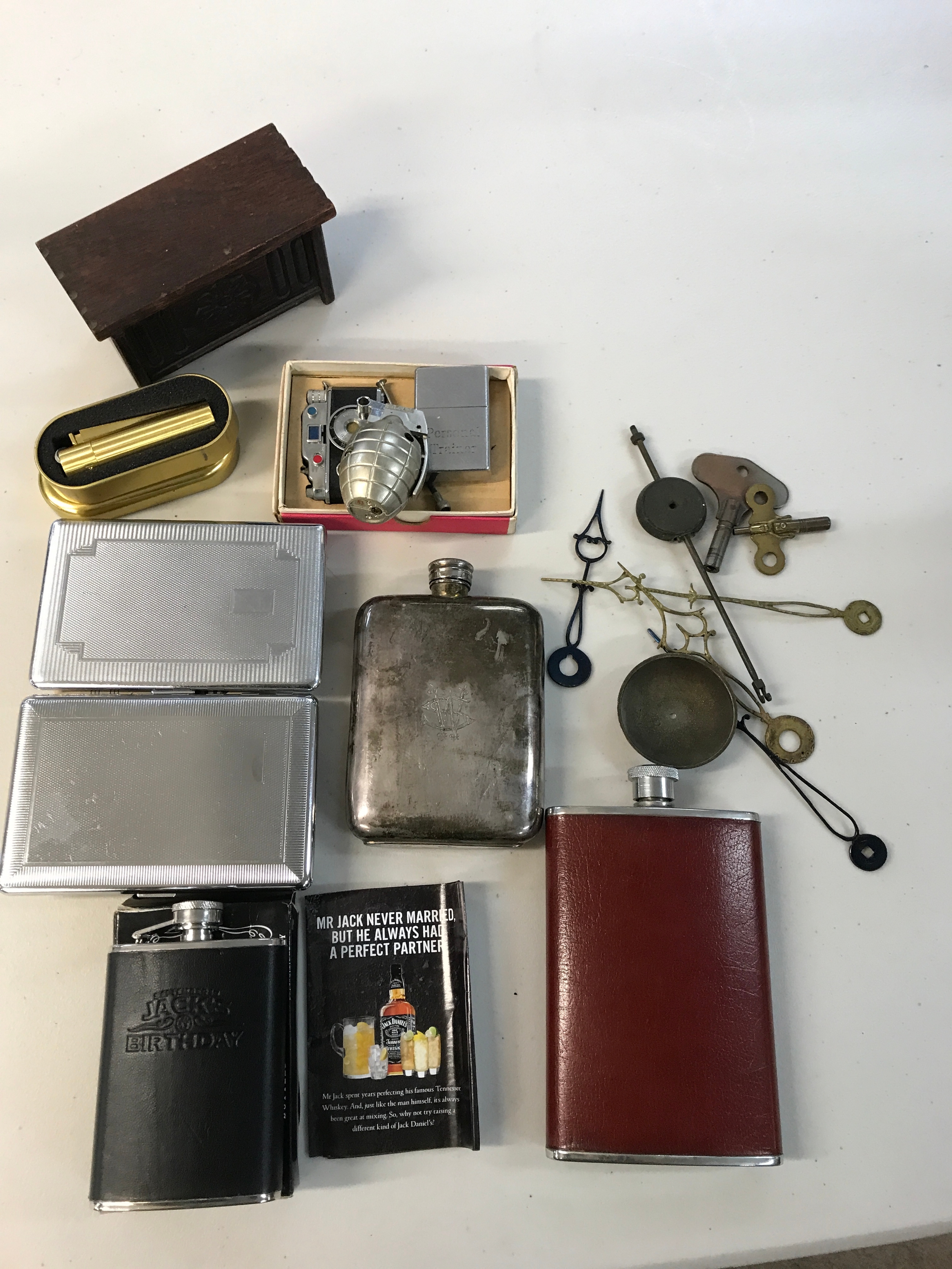 A collection of hip flasks and lighters including a novelty camera lighter. Spare clock parts 