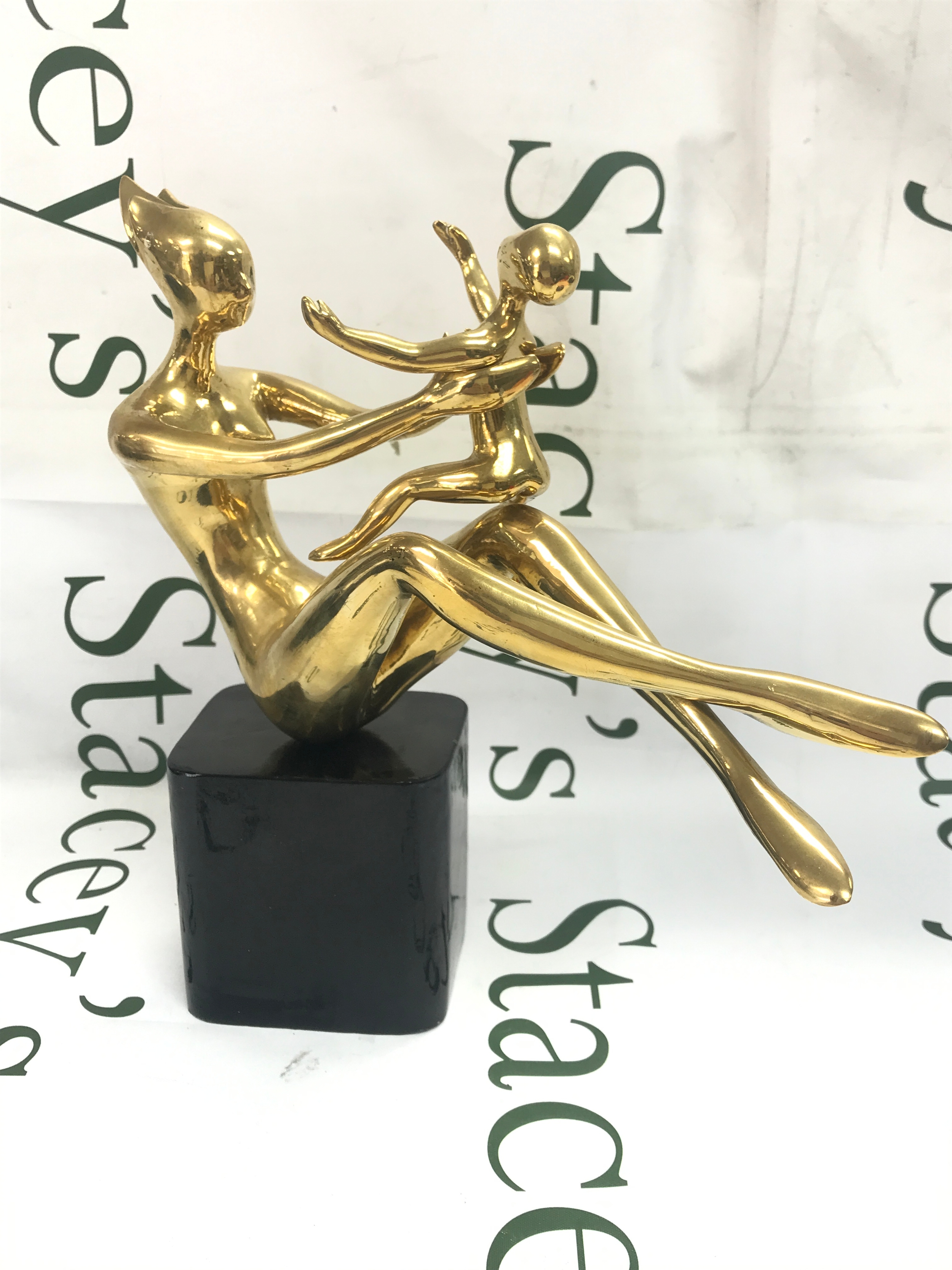 A modernist abstract brass sculpture featuring a mother holding a child. Marked Sura Wongse 11/1000. 28cm tall, 27cm wide