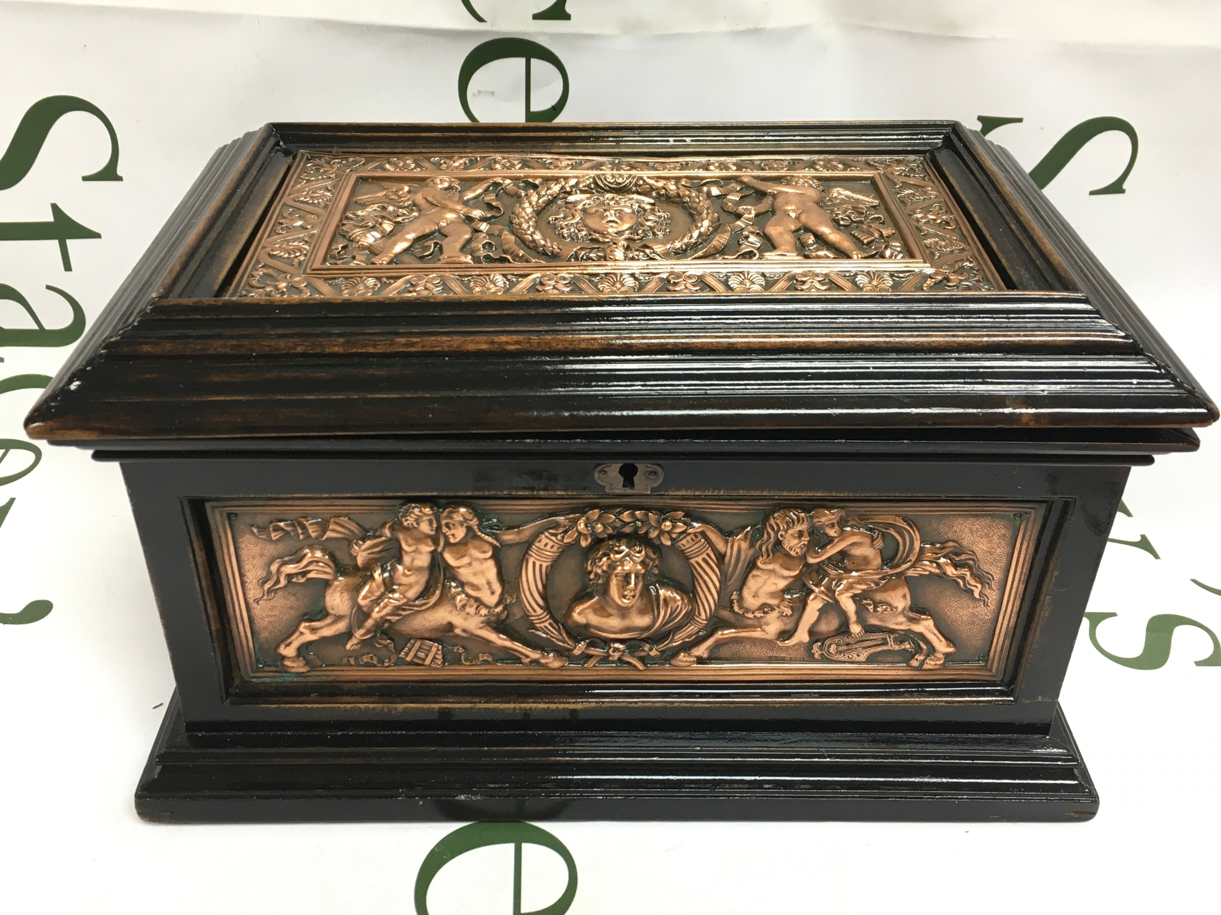 A wooden jewellery/ cigar box decorated with copper panels of intricate classical figures. 25cm wide 16.5cm long 14cm tall. Marked E&S edit