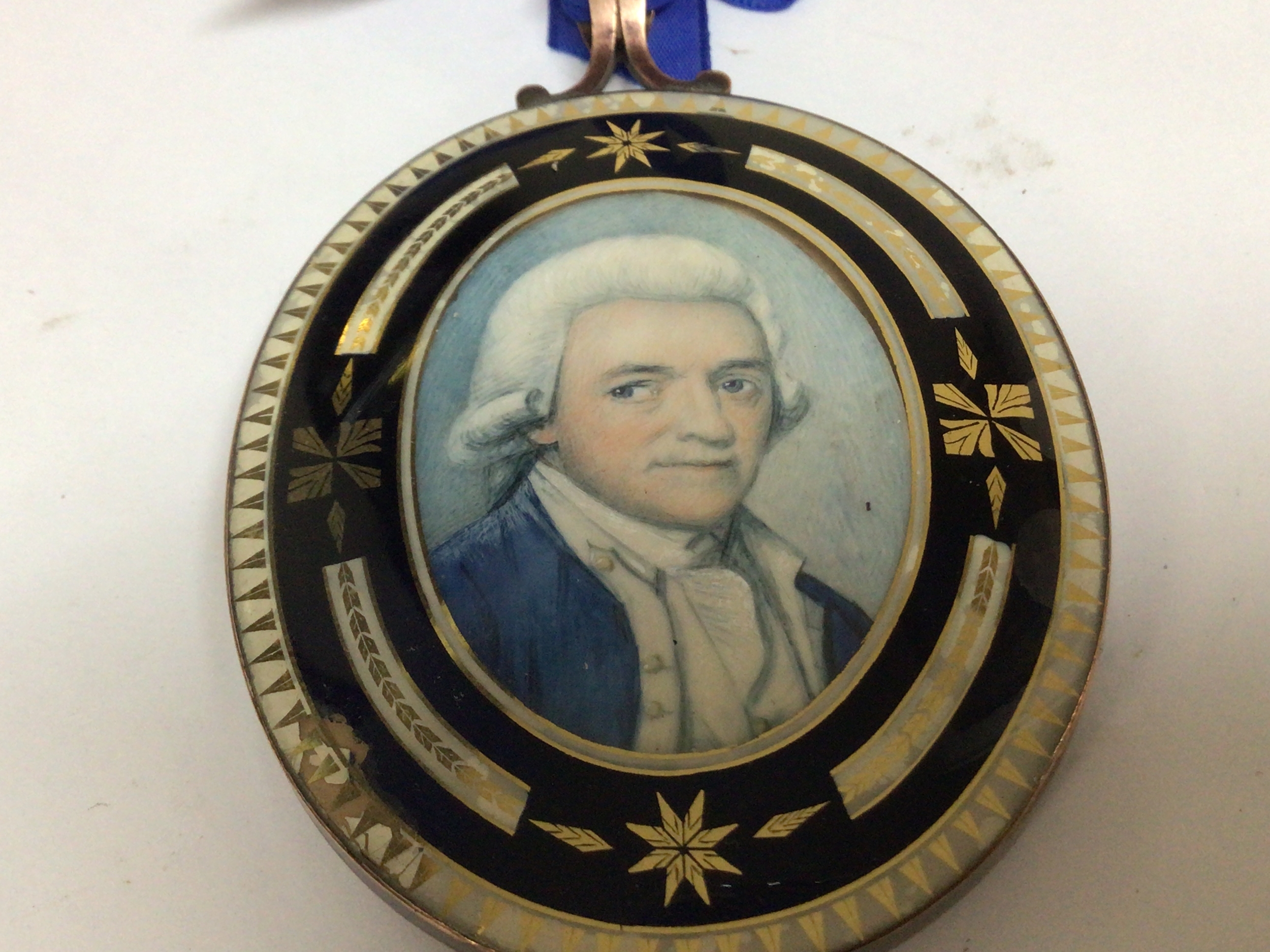  A late George III oval portrait miniature Mourning pendent depicting a Gentleman possibly a Navy officer the frame with enamel decoration the reverse with initials and hair 8.5cm slight damage to the enamel.