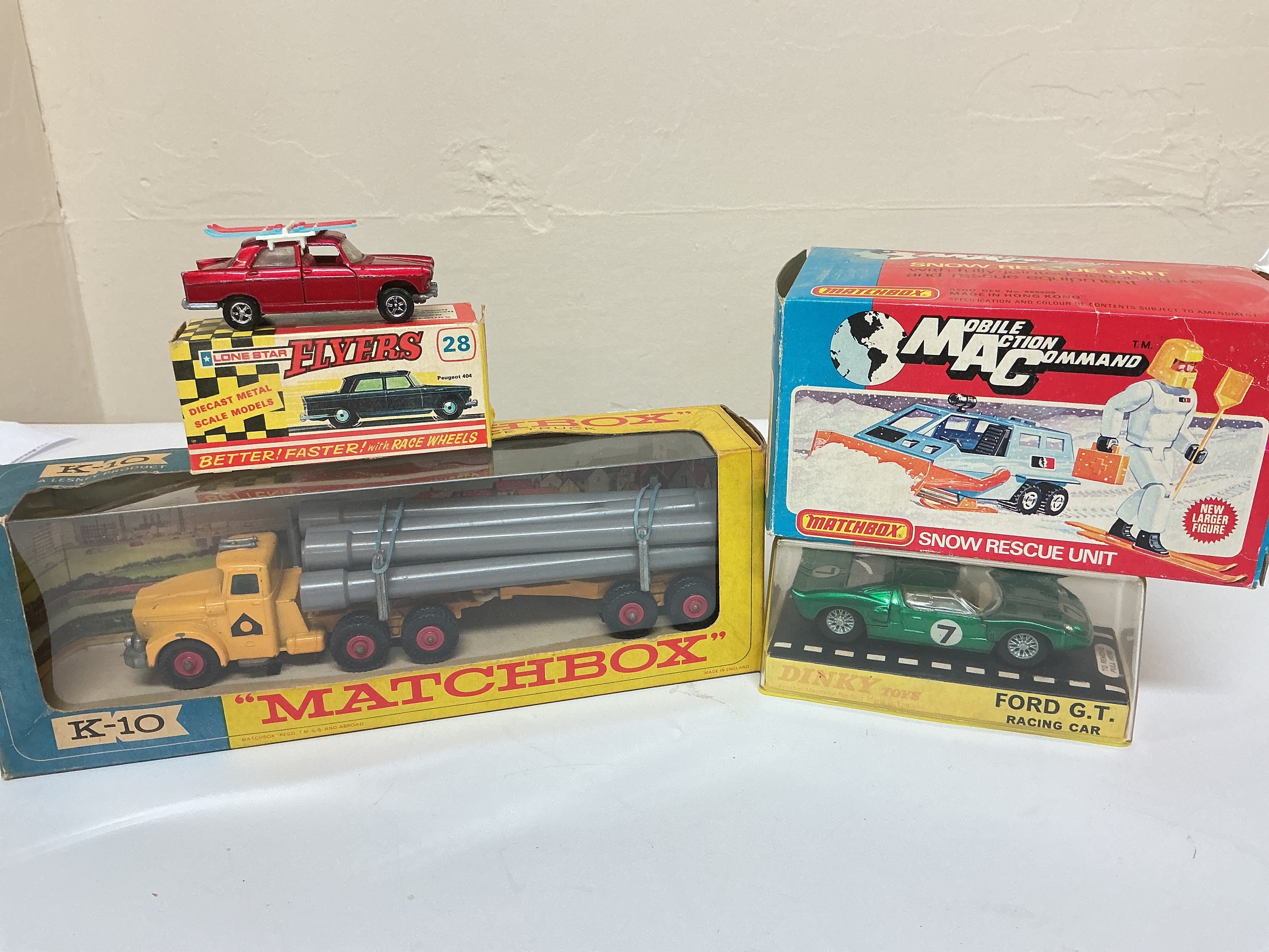 A Boxed Matchbox Pipe Truck #K-10, A Lone Star Peugeot 404, A Matchbox Mobile Action Command Snow Rescue Unit And A Dinky Ford G.T. Racing Car #215.