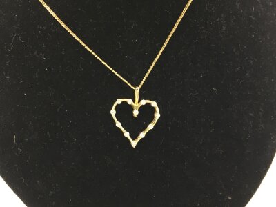 An 18ct yellow gold heart shaped pendant set with diamonds on a 9ct chain.
2.94g