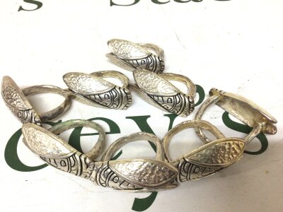 A set of eight white metal napkin rings in the form of arabesque insects. Unmarked.
