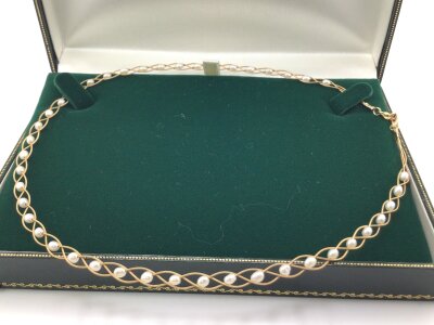 A 9carat gold necklace woven with cultured pearls in a fitted Ernest Jones box.