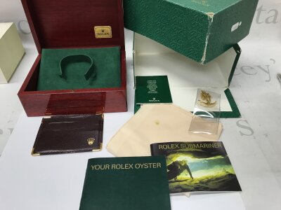 A Rolex box and some accessories for a 118208 day date. Includes a submariner booklet and a gilded anchor.