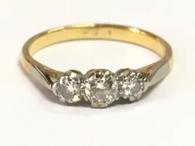 An unmarked 18ct gold and platinum three stone diamond ring size M. 2.4g total weight. Central stone approximately 0.25ct