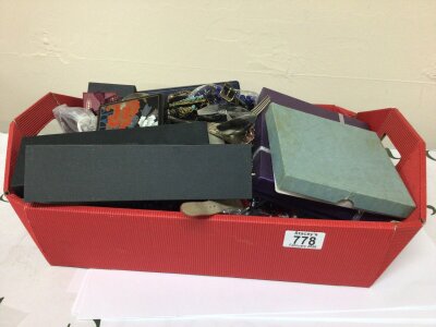 A red tray containing a collection of costume jewellery watches and other ornaments.