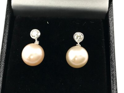 A pair of 9ct white gold articulated earring set with diamond bales and suspended pink cultured pearls.