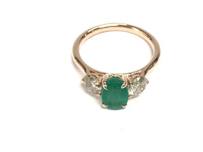 An 18ct rose gold oval emerald and diamond three stone ring. Emerald 1.55ct and diamonds 1.01ct approximately.  Size N