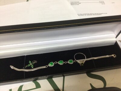 A silver bracelet set with emerald coloured stones a ring and small cross pendant.