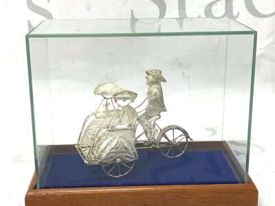 A filigree silver rickshaw figurine (7 m tall) in a display case