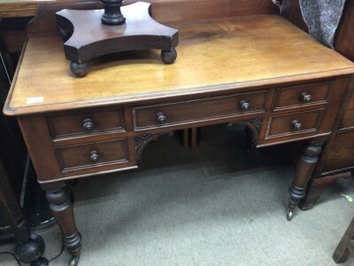 A Victorian Mahogany table with a raised back above four drawers on turned legs.- NO RESERVE