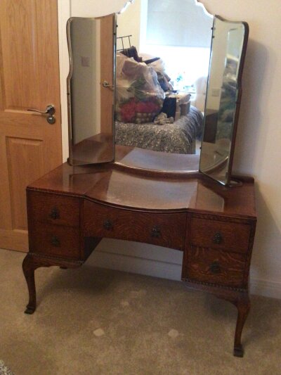 A Tiger Oak bedroom suite comprising a bow fronted wardrobe with applied moulding dressing table with triple mirror and a low boy with cupboards and drawers.