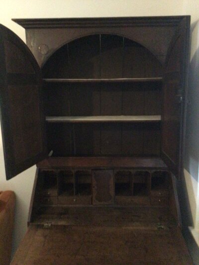 An 18th Century George III oak bureau bookcase with a pair of arch panelled doors above a fall front enclosing a fitted interior above two short and three long drawers.