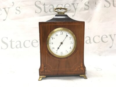 An Edwardian clock in a mahogany inlaid case with brass handle, feet and key. Made in France