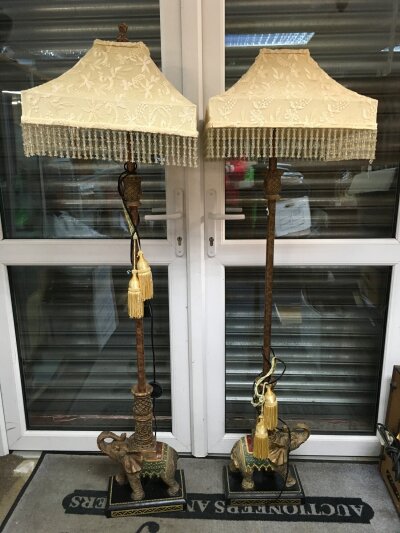 A pair of standard lamps, the turned columns supported by elephants on square bases