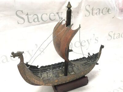 An old heavy brass model of a Viking ship with sail, on a wooden stand. 37cm tall, 40cm wide