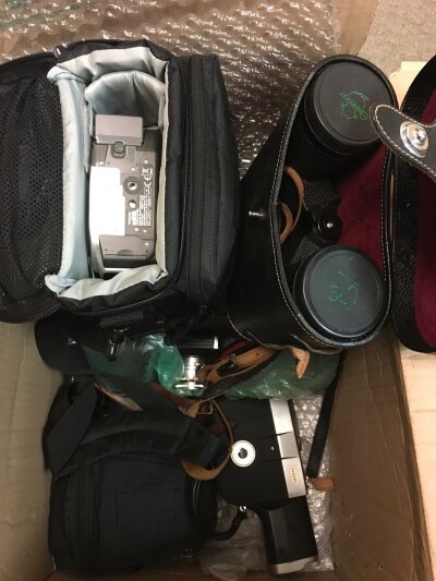 A box containing various camera equipment and a pair of binoculars