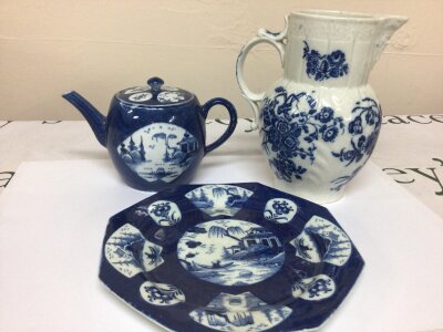 A Collection of three nice examples of English 18th century porcelain comprising a mask head with impressed pattern and sprays of blue flower's possibly from the Caughley factory hight 18cm with hair line cracks. An 18th Bow Porcelain plate circa 1765 some restoration and a conforming tea pot decorated in the Chinese style. (3)