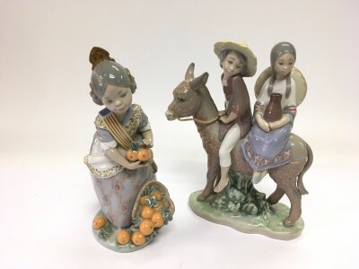 Two Lladro figures comprising a boy and a girl seated in a donkey plus a girl with fruit, both approx 19cm.