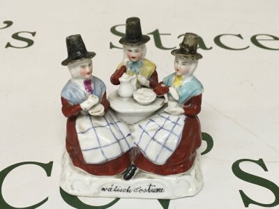 Welsh Tea Party Group. 
Paint work faded in areas. Cracks on left seated figure and in the centre.