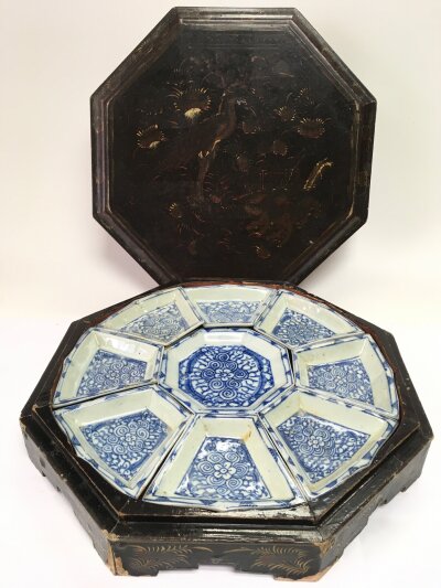 A Chinese blue and white set of shallow dishes housed in an octagonal lacquered box.