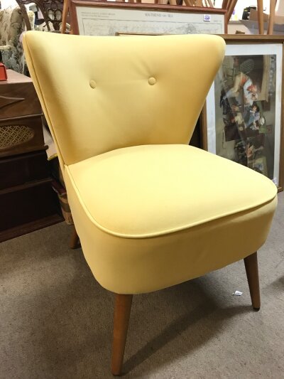Mid 20th century design yellow velvet cocktail chair featuring a distinctively curved backrest with two button tufts and splayed wooden legs. 61cm wide 80cm tall 58cm long