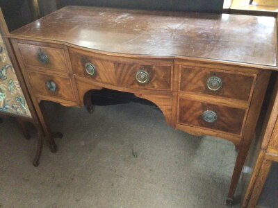 An Edwardian satinwood banded mahogany sideboard fitted with four drawers with a shaped front on square tapering legs.