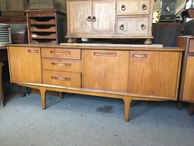 A modern Teak sideboard fitted with three drawers and three cupboards