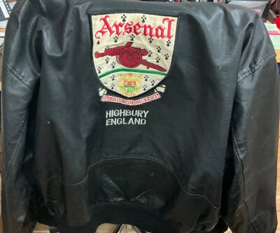 Arsenal Football Garments: Fair condition size XL leather jacket with old Arsenal cloth badge to front and back with the words Highbury London. The label reads Who Wears Wins and is possibly 1990s. C/W 3 football shirts  from the late 1990s in men’s sizes which are fair/good. (4)