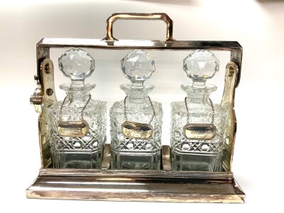 A silver plated 3 bottle tantalus with 3 hallmarked silver wine labels.