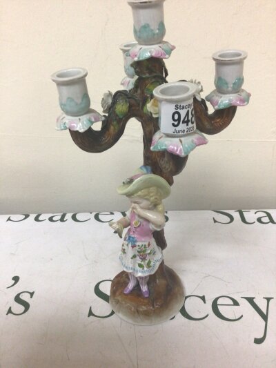 A Porcelain late 19th century candelabra with a young girl standing on a naturalistic base impressed marks to the base. 35cm high.