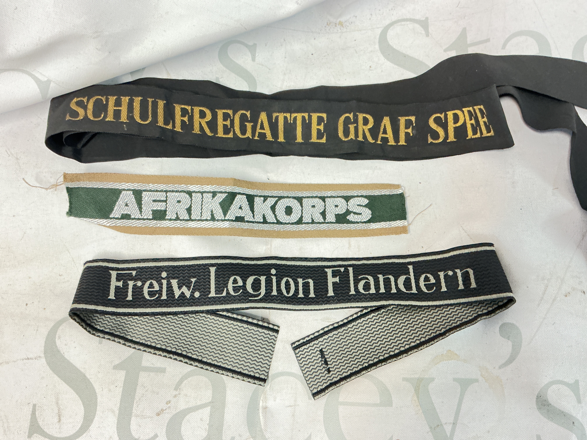A Kreigsmarime Cap Tally Training Ship Graf Spee, Afrika Corps Cuff Title And Bevo SS Cuff Title Legion Flandern Maker Marked.