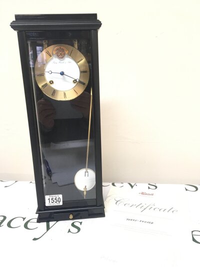 A German Heimle HUM Uhrenmanufaktur wall clock with lacquered brass and enamel dial with visible escapement. With key in the fitted drawer  Sold with purchase certificate. Hight 44cm